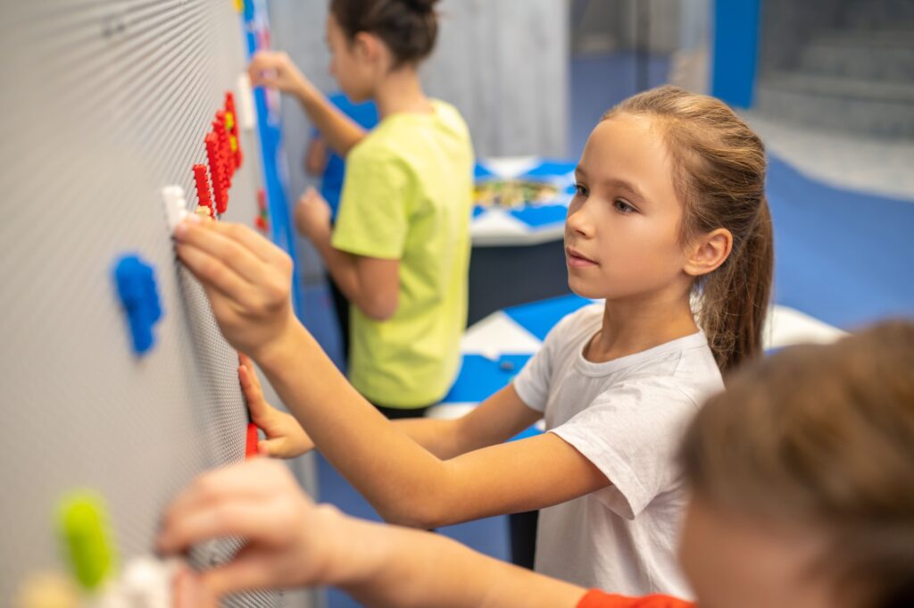 girl-attaching-lego-piece-wall-min